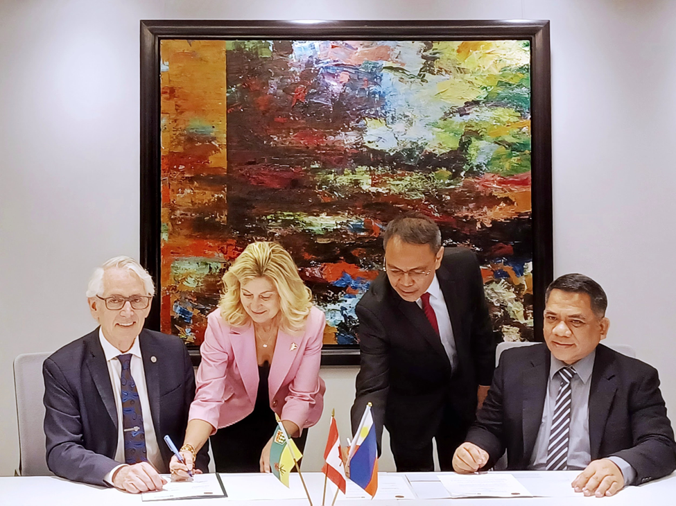 Dr. Peter Stoicheff (left) President of the University of Saskatchewan (USask) and Dr. Jose D. Camacho, Jr. (right), Chancellor, University of the Philippines Los Baños signs the MOU on Academic and Research Cooperation on 20 February 2023. Behind them were witnesses Ms. Cheryl Hamelin, Vice President, University Relations of USask and Dr. Nathaniel C. Bantayan, Vice Chancellor for Research and Extension, UPLB.